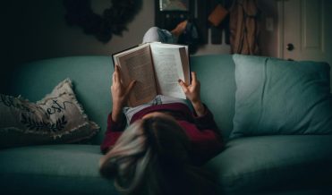 A woman reading a book on a couch