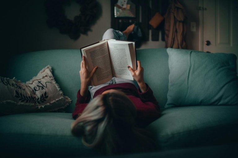 A woman reading a book on a couch